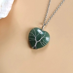 Macro shot of silver wire tree of life wrapped on a heart shaped green stone necklace