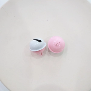 Close-up of candy-colored metal bells for DIY keychains in pink and white paint finish