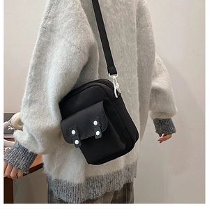 Model wearing a minimalist black canvas crossbody bag with adjustable nylon strap for travel