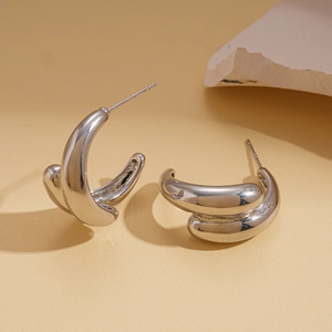 Macro detail of thick silver C-shaped hoop earrings with a high-polished metallic finish