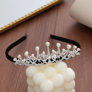 Detail of silver crown headband with sparkling rhinestones and pearls on black velvet base