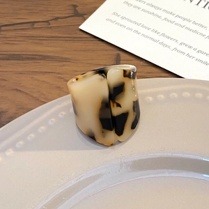 Macro shot of irregular tortoise shell acrylic ring on a white plate and wooden desk