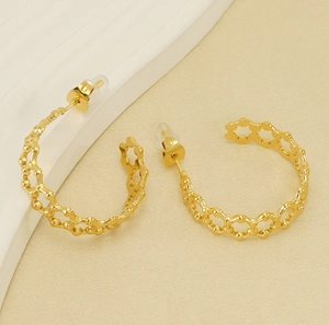 Dettaglio di orecchini a cerchio placcati oro 18K con motivo esagonale a nido d'ape e silicone