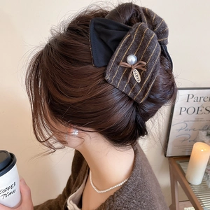Gros plan d'une pince à cheveux avec nœud en tissu rayé marron et perle élégante