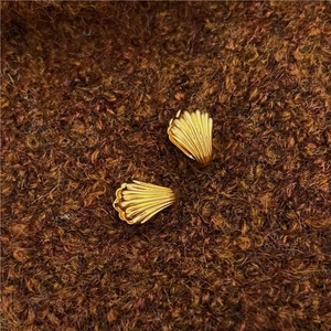 Detailed macro shot of 925 silver shell-shaped golden earrings with ribbed texture