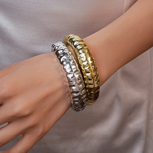 Detail of gold and silver hammered metal cuffs with modern irregular texture on wrist