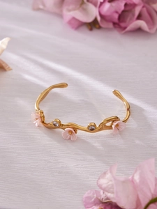 Detail view of flower bangle with gold finish, pink petals, and sparkling zircons