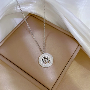 Detailed view of silver tree of life pendant with sparkling crystal halo on silk fabric