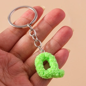 Detailed macro view of letter Q keychain featuring embossed green rose floral patterns