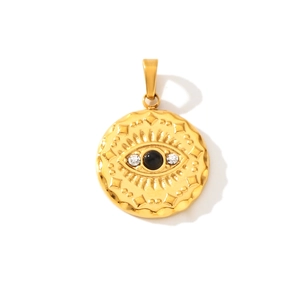 Detail of gold evil eye pendant featuring black gemstone and embossed craftsmanship