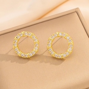 Dettaglio di orecchini a cerchio placcati oro con micro-pave di cristalli su base beige