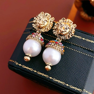 Detail of lion head earrings with colorful crystals and white teardrop pearls