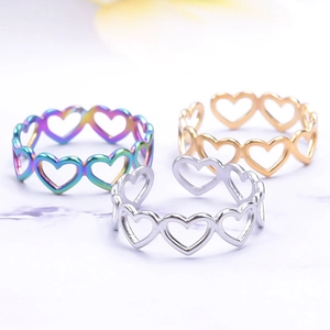 Three minimalist heart cutout open rings in gold, silver and rainbow on white marble