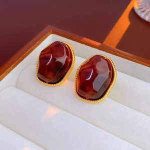 Detail of vintage irregular brown resin earrings with gold woven metal edge in a box