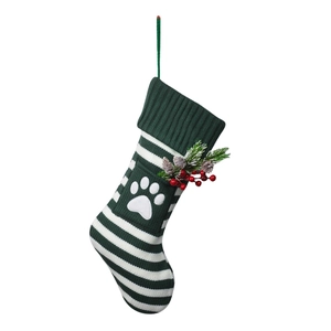 Close-up of green and white striped knit Christmas stocking with a white paw print