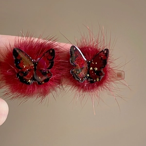 Detail of red plush heart earrings with a gold-dusted resin butterfly embellishment