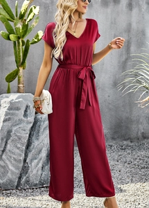 Detail of short sleeve V-neck jumpsuit in wine red featuring waist tie and wide leg cut