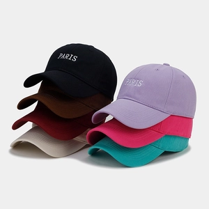 Close-up of stacked cotton baseball caps in multiple colors with white PARIS embroidery