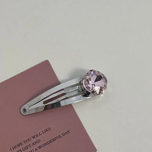Detailed view of silver hair clip with a large faceted pink crystal on decorative card