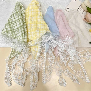 Lace-trimmed floral and solid triangle headscarves in assorted colors on a wooden surface