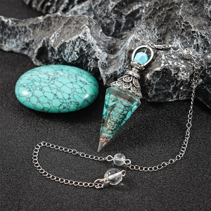 Macro view of dowsing pendulum with turquoise stones and copper coil on rock surface
