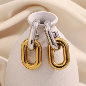 Detail of hollow chain link earrings in gold and silver finish on a ceramic vase