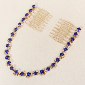Close-up of gold bridal hair comb with blue gems and clear crystals on beige texture
