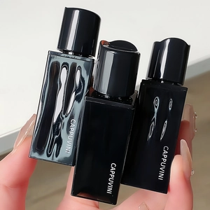 Detailed close-up of three black glossy Cappuvini velvet lip glazes held in hand