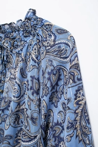 Dettaglio della camicetta in chiffon paisley blu con colletto a ruches e lacci boho