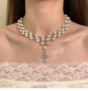Detail of double-layer pearl choker with a zircon cross pendant on a female neck