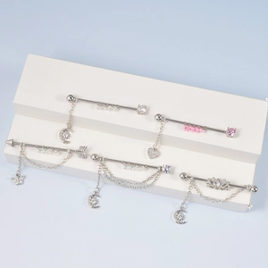 Cinq boucles d'oreilles barre en acier avec pendentifs cœur et lune sur socle bleu