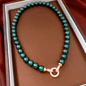 Close-up of luxury peacock green pearl necklace with a diamond-encrusted gold ring clasp