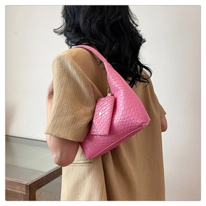 Pink woven texture handbag with detachable mini pouch carried by a model over the shoulder