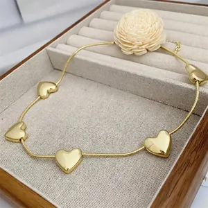 Detail of 18k gold plated snake chain necklace with five heart charms in jewelry box