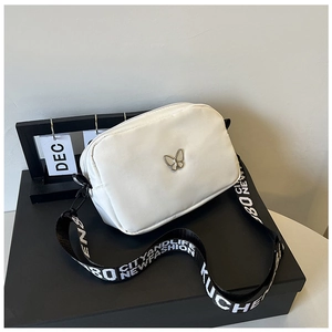 Detail of white nylon crossbody bag with silver butterfly and lettered strap