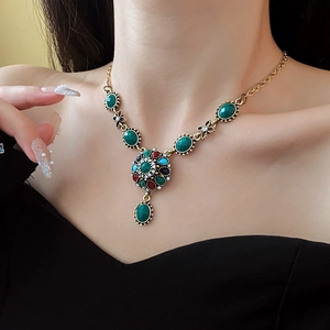 Macro shot of vintage gold necklace with green red and blue rhinestones on model