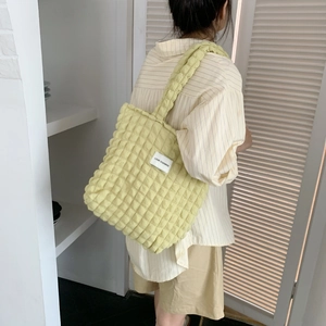 Dettaglio della trama in tessuto a bolle giallo chiaro su una borsa a tracolla minimal