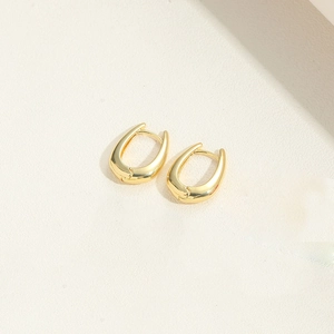 Detail of gold-plated U-shaped snake earrings with a glossy metallic finish