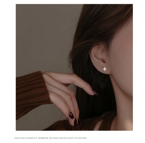 Close-up of star-shaped zircon earrings in S925 silver worn on a female ear model