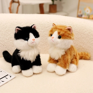Realistic sitting tuxedo and ginger plush cat toys on a soft white fleece sofa