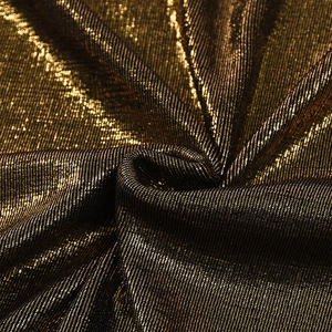 Detail of metallic gold and black fabric texture with shimmering sequins and pleated finish