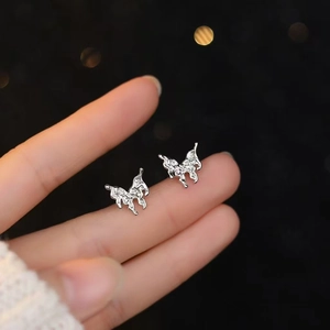 Macro shot of butterfly zircon sterling silver stud earrings held with blurred background