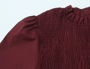 Gros plan sur le tissu smocké bordeaux avec un col montant volanté élégant et texturé