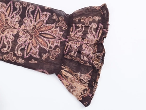 Detail of bohemian flared chiffon sleeve featuring intricate paisley prints in dark brown