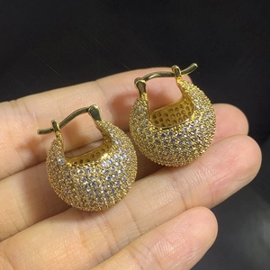 Sparkling pave-set zircon ball earrings in gold plating shown in hand with black background