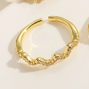 Détail d'une bague vague plaquée or 14K ornée de zircons roses sur une texture blanche