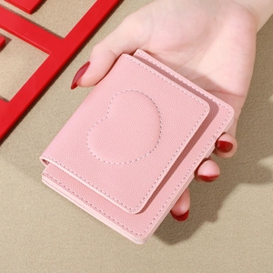 Pink pebbled leather small wallet for women featuring heart stitching in a hand-held view