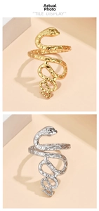 Close-up of gold and silver snake rings with textured scale details on a beige background