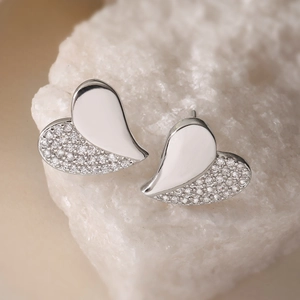 Exquisite silver heart stud earrings with cubic zirconia on a natural stone background