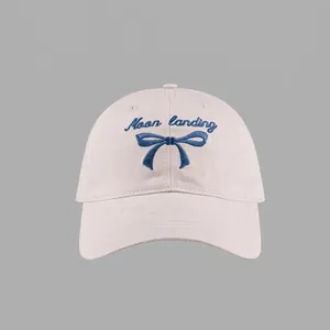 Detail of light pink baseball cap showing navy blue Moon landing embroidery and bow pattern